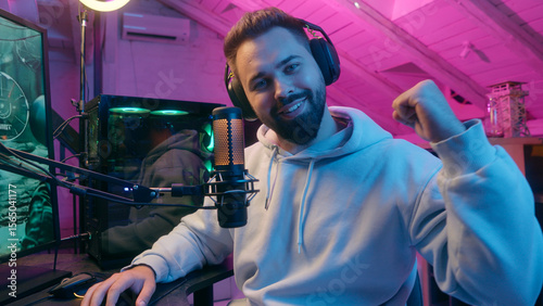 Caucasian smiling talking microphone at camera guy male gamer man streamer influencer blogger in headphones record channel online vlog chat talk e-sport video game cyber sport addict radio presenter