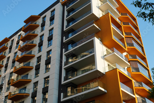 New apartment building exterior with balconies and windows. Modern design in white and yellow colors.