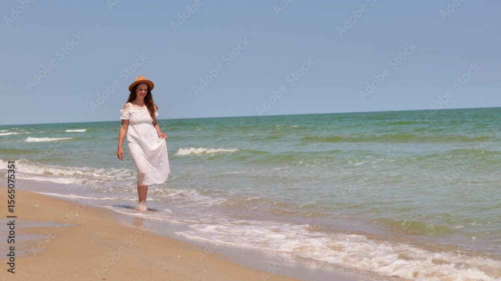 A cheerful woman in a white dress and straw hat walks barefoot along the sandy beach, enjoying the refreshing ocean waves. A cheerful woman in a white dress and straw hat walks barefoot along the sandy beach, enjoying the refreshing ocean waves.