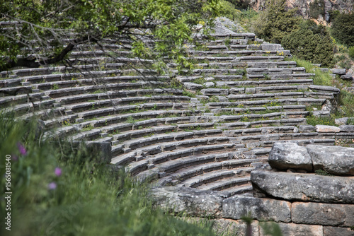 The gray ruins of ancient Delphi sit quietly under a partly cloudy sky, showing signs of age and history.