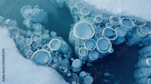 Frozen lake bubbles trapped under ice forming cellular structures. Cool blue/white palette with subtle turquoise undertones