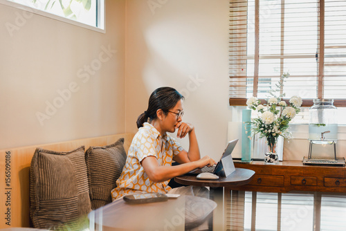 Woman hand cover her mouth while working on laptop.
