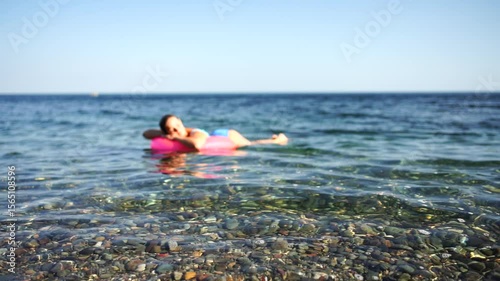Summer vacation happy woman floats on an inflatable donut mattress, pink swim ring. Summer travel holidays vacation on the sea.