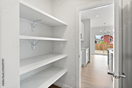 White pantry with shelves and a door leading to a kitchen