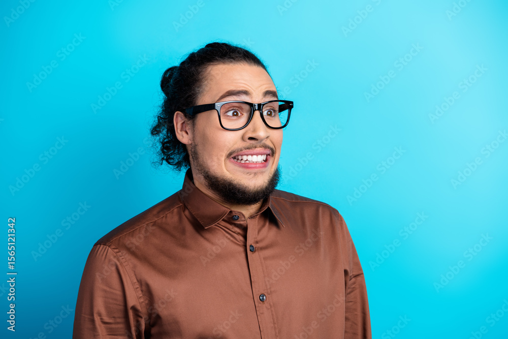 Fototapeta premium Professional young man with a humorous expression in elegant attire standing against a vibrant turquoise background
