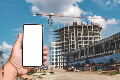 Hand Holding Smartphone with Blank Screen at Construction Site