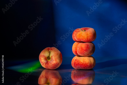 Stack of flat peaches on dark reflective surface