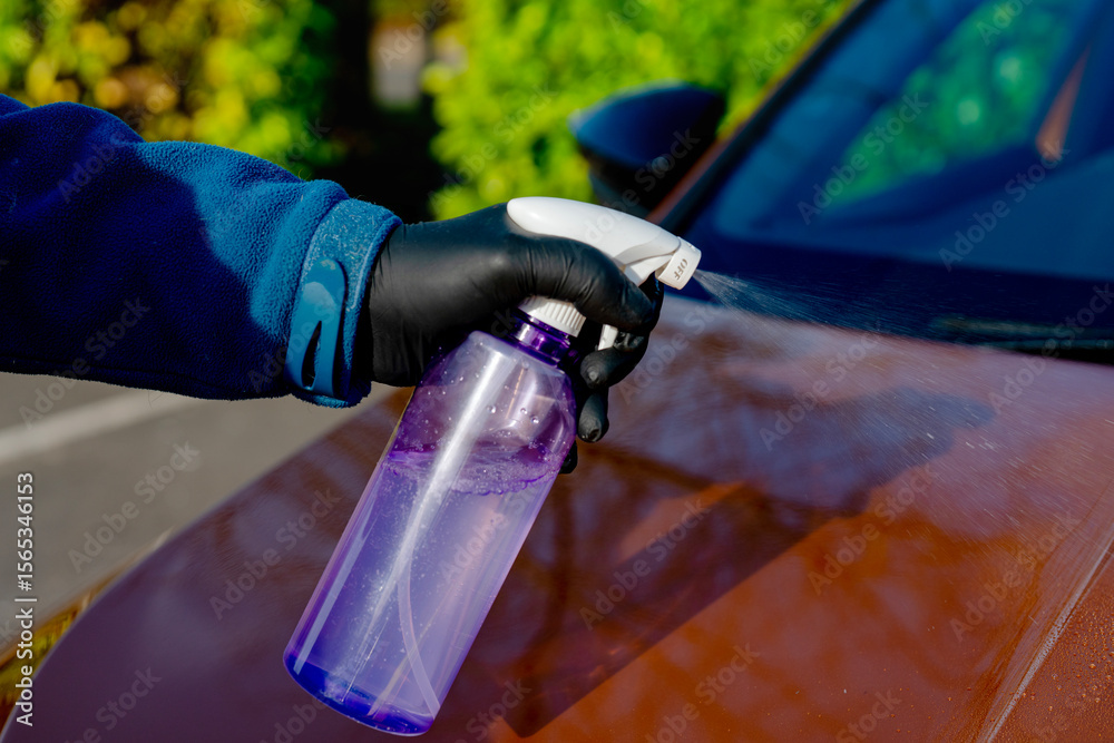 Naklejka premium Applying liquid ceramic coating to vibrant orange car panel to protect it from scratches, chips and ultraviolet damage. Applying nano coating for long lasting car paintwork