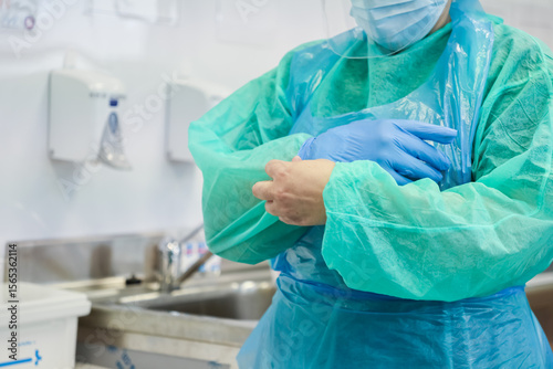 Tableau sur toile Healthcare professional in full green PPE, face shield, and mask, preparing to p