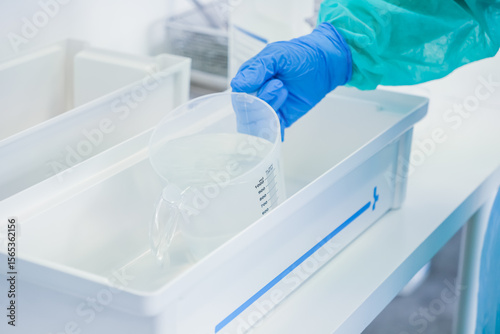 Fotografie Close-up view of a medical worker's gloved hand accurately pouring solution from