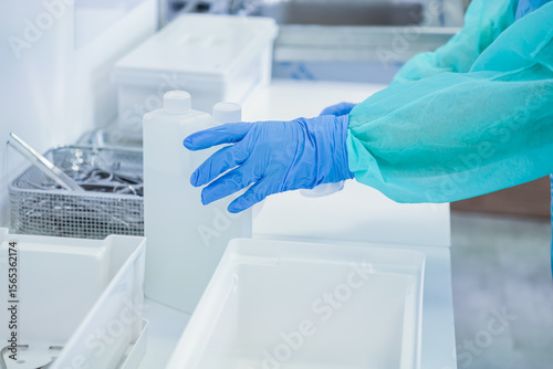 Canvas Print Close-up of medical worker's gloved hand and protective sleeve, handling disinfe