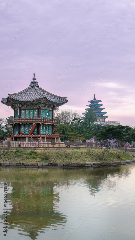 Obraz premium Seoul, South Korea - April 9, 2025: Hyangwonjeong Pavilion at Gyeongbokgung Palace reflected in the calm pond under a cloudy sky, highlighting traditional Korean architecture.