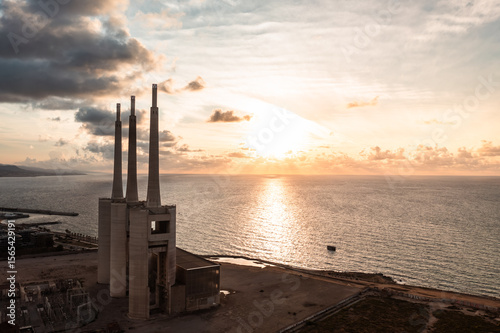 Sant Adrià de Besòs Power Plant: Industrial Icons at Sunset

An aerial view of the disused power plant's three towering chimneys against a dramatic sunset over the Mediterranean Sea near Barcelona.