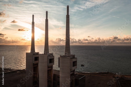 Sant Adrià de Besòs Power Plant: Industrial Icons at Sunset

An aerial view of the disused power plant's three towering chimneys against a dramatic sunset over the Mediterranean Sea near Barcelona.