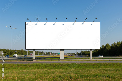 Large blank billboard on the side of a highway with road, guardrails, and distant cars under clear daylight, ideal for outdoor advertising mockup.