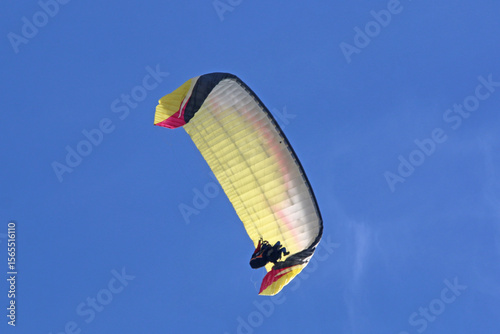 Tandem Paraglider flying in a blue sky	