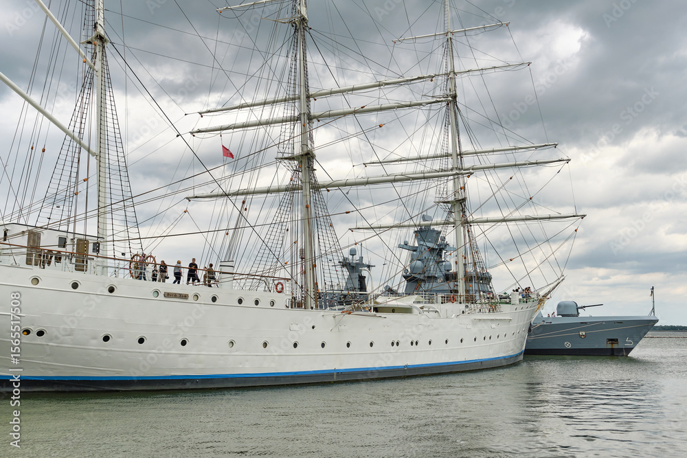Obraz premium Bark Gorch Fock I and bow of German corvette in Stralsund harbor under heavy clouds