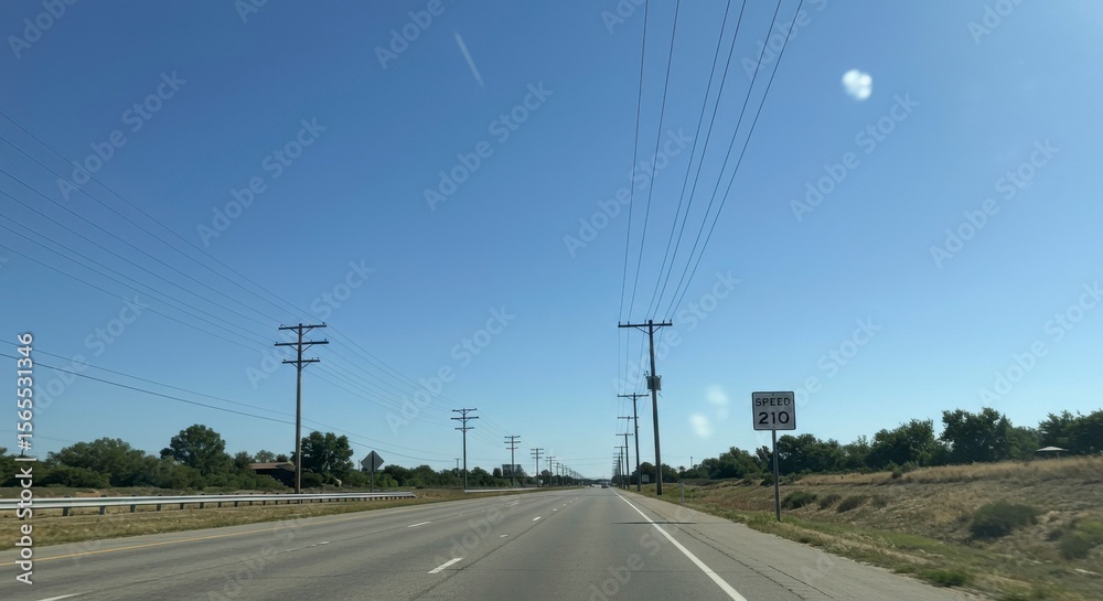 Fototapeta premium Sunny highway scene with power lines, clear blue sky, and speed limit sign