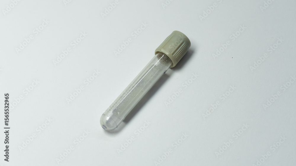 Naklejka premium A single empty blood collection tube with a gray cap placed diagonally on a white background. Commonly used for glucose testing in medical laboratories.