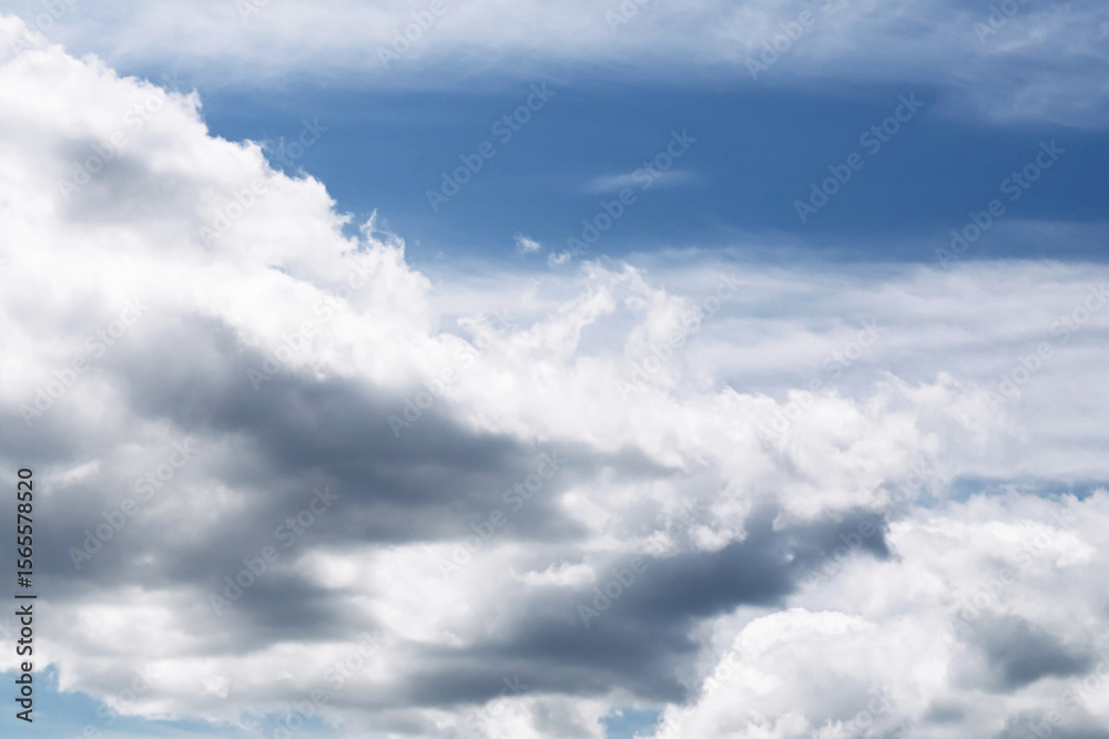 Fototapeta premium Dramatic cloudy sky background. Beautiful layered clouds in blue sky. Natural weather scene with white and gray formations. Peaceful and moody sky texture. Ideal for design or backdrop projects.