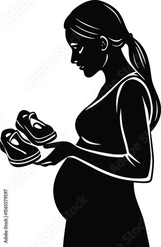 Silhouette side view of a pregnant woman holding tiny baby shoes over her belly