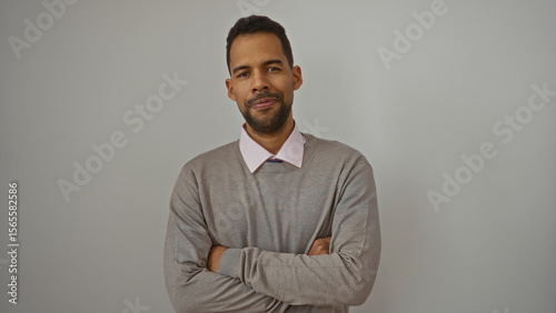 Φωτογραφία Young hispanic man standing confidently with arms crossed isolated against white background, exuding charm and confidence in a relaxed casual attire with neutral expression