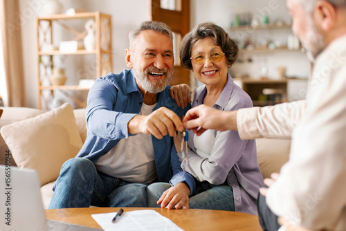 Realtor giving senior couple key to new house at meeting, owners making purchase deal, family bought or rented apartment