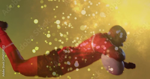 Golden particles intensifying then football player diving through haze holding ball exiting frame