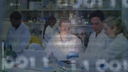 Seated scientist examining samples and driving circuit visuals while lab team pipetting test tubes
