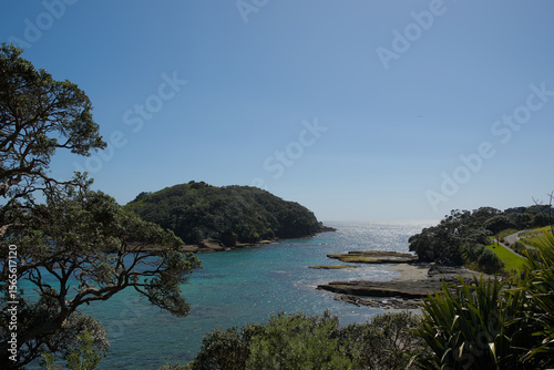 Wallpaper Mural A vast coastal landscape features a long sandy beach, a turquoise ocean with distant islands, and rolling green hills under a bright blue sky with scattered clouds. Torontodigital.ca