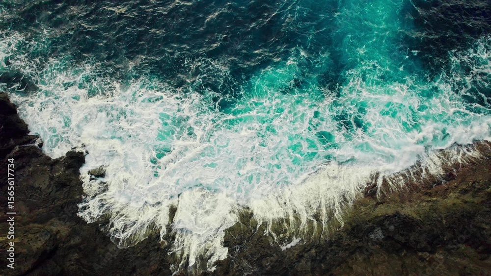 Obraz premium The sea is beating against the rocks on the shore. Bird's-eye view. Frothy waves from a drone