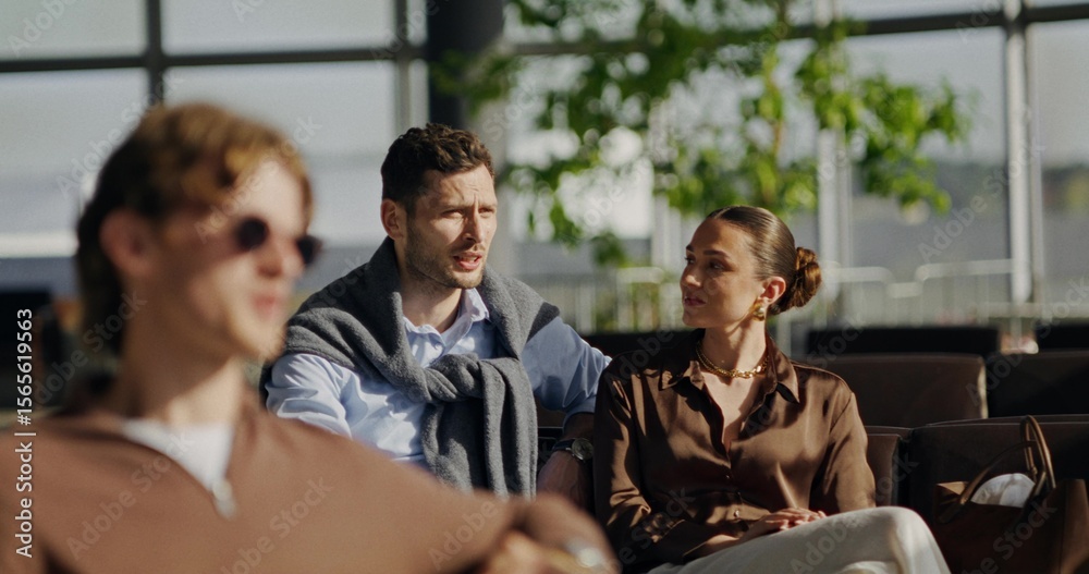 Obraz premium Stylish young man and woman are talking while sitting in an airport or train station waiting room