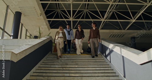 A group of stylish young people descend the stairs indoors