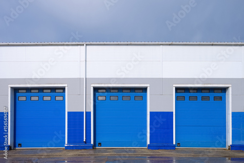 Row of overhead sectional gates in a multi-seat cargo truck garage. Outdoors front view.