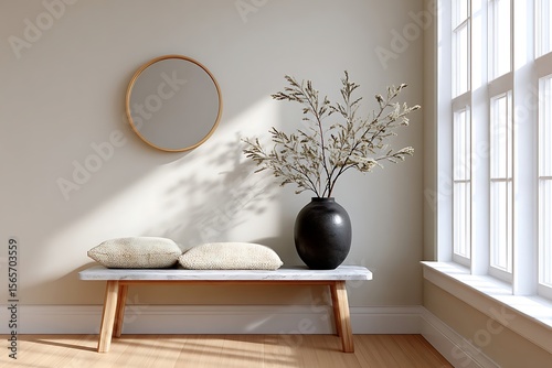 Inviting entryway with a bench textured pillows vase and round mirror creating a serene minimalist aesthetic.