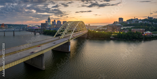 Downtown district of Cincinnati city in Ohio, USA at sunset with driving cars traffic on Daniel Carter Beard Bridge and brightly illuminated high skyscraper buildings. American travel destination