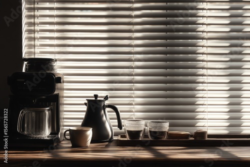 Coffee maker and cups on a wooden surface by a window with blinds