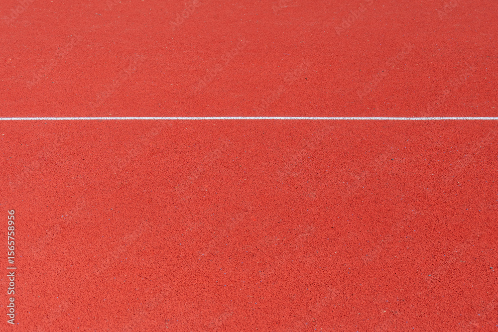 Fototapeta premium A vibrant red surface designed for athletic activities highlights the area where runners will compete. This track is suitable for various sports events