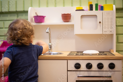Baby boy playing with a toy kitchen