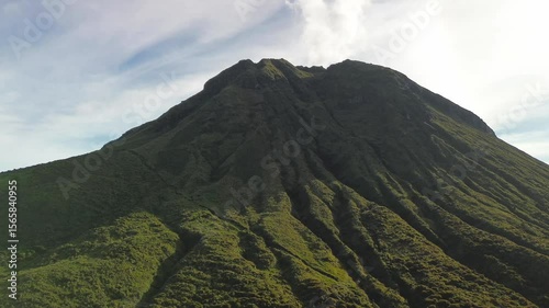 Wallpaper Mural Low-level flyby along Mount Apo’s green volcanic flanks reveals deep erosional ribs and a faint steam plume curling into a pastel morning sky. Torontodigital.ca