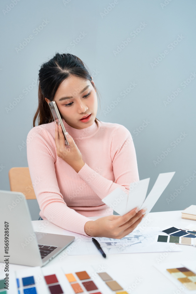 Interior designer talking on cellphone with client, discussing new project, In studio office with blueprint drawing color swatches and material, design develop, Copy Space Interior designer talking on cellphone with client, discussing new project, In studio office with blueprint drawing color swatches and material, design develop, Copy Space