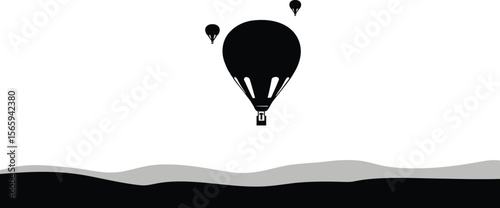 Black and white scenic view with hot air balloons floating against a bright sky over a grayscale landscape.