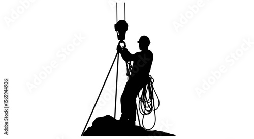 Silhouette of a construction worker attaching a load to a crane hook, wearing a hard hat.