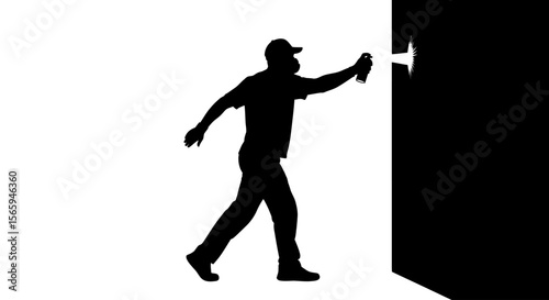 Silhouette of a person spraying paint on a wall, creating art.