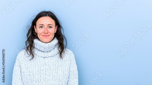 Woman in white sweater against light blue background looking at the viewer.
