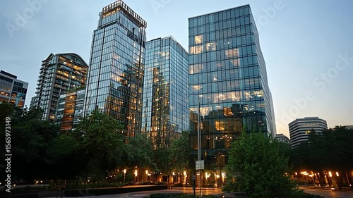 Wallpaper Mural A low angle shot of several glass-fronted buildings at dusk with warm interior lights, captured on a cloudy evening. The buildings are bordered by trees and illuminated walkways, creating an urban Torontodigital.ca