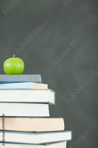 Green apple in front of blackboard on books