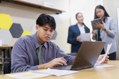 Young man is intensely focused on his laptop while seated at desk.