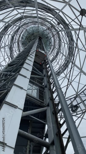 An elevator cabin with passengers rises up in a steel tower.