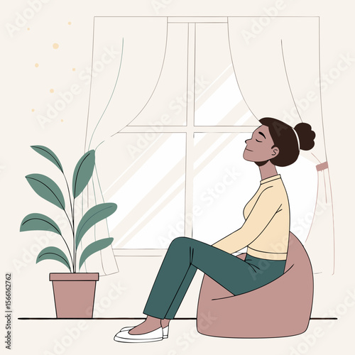 A woman is sitting on a beanbag chair near a window with curtains and a potted plant in a cozy room space
